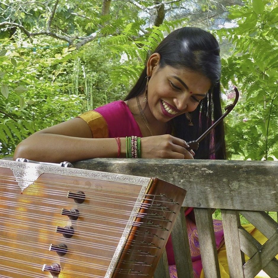 Umadevi Nageswara Rao, souriante, penchée sur un santour dans un jardin