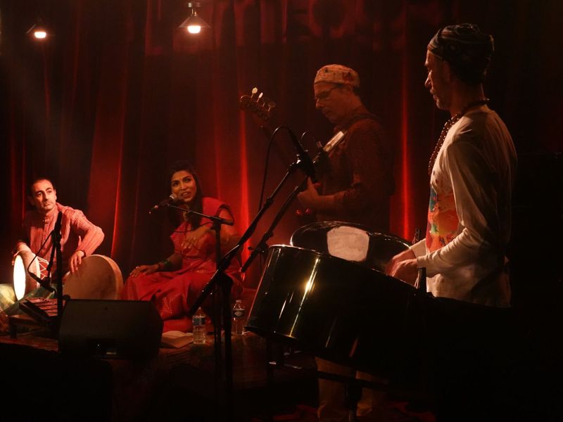 Quatre musiciens sur scène devant un rideau rouge
