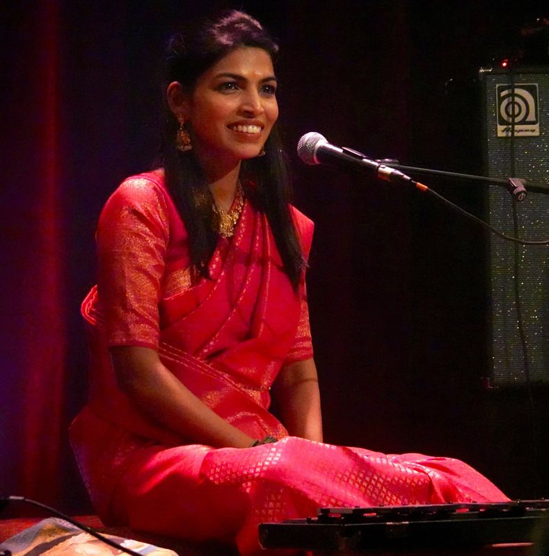 Umadevi Nageswara Rao, souriante, en sari rouge, au micro